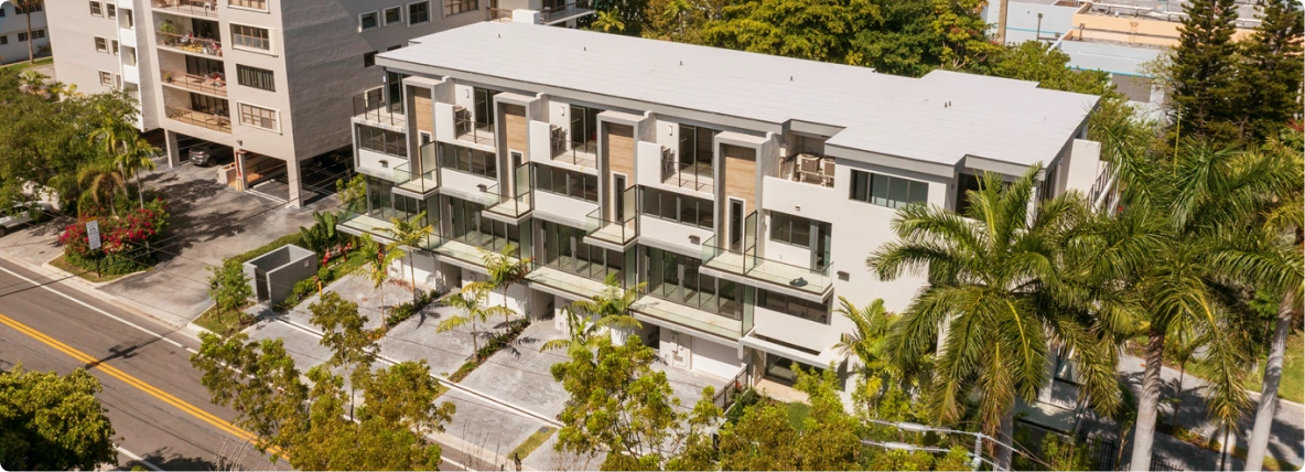 Aerial view of a completed modern residential building surrounded by palm trees