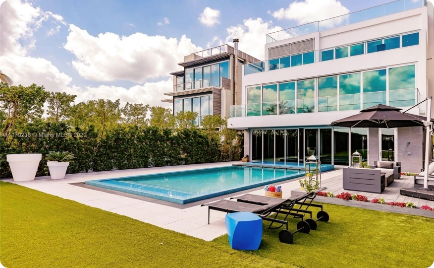 Modern home exterior with swimming pool, lounge seating, and glass balconies